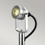 A detailed view of the Spennymoor 1 x 12V Spotlight and Pole in a sleek silver finish, featuring a circular head with an array of small LED bulbs. The low voltage fixture is mounted on a pole with a 1-meter black cable extending from the rear, set against a simple light gray background.