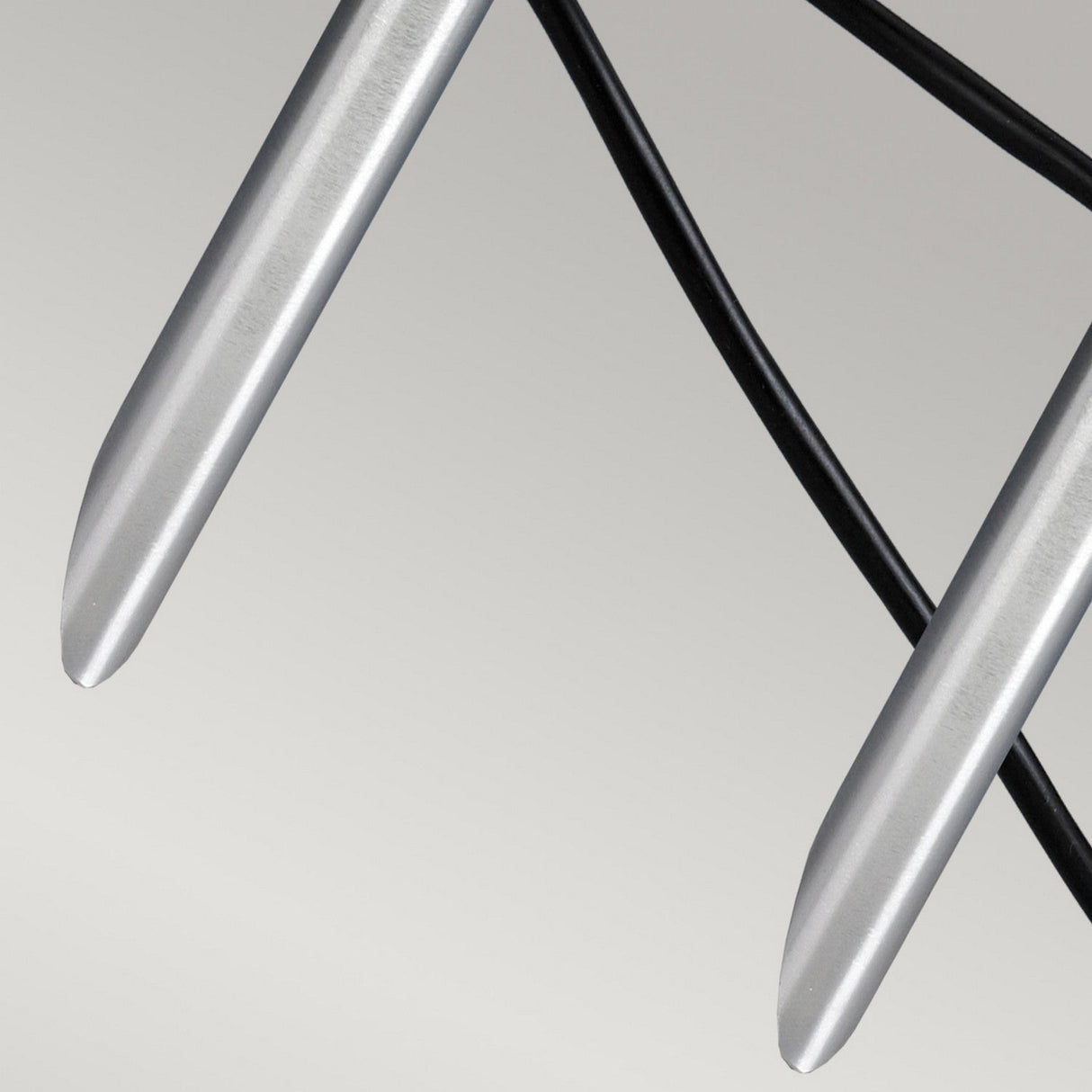 A close-up image features two sleek, silver Spennymoor 12V Spotlights with pointed tips crossing over each other against a plain background. Beneath them, a black curved line resembling the included cable suggests their outdoor lighting application.