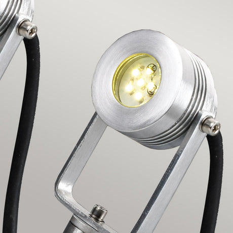 Close-up of the Spennymoor Kit's modern 12V spotlight featuring a sleek silver metallic finish, highlighting its circular light head with visible small LED bulbs. The spotlight is mounted on a black and silver bracket against a neutral background, making it perfect for enhancing outdoor lighting setups.