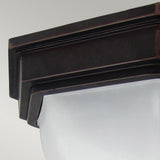 Close-up of the Fairford 1 Light Outdoor Flush Lantern in a black, geometric design made from cast aluminium. It includes a frosted glass shade and has an IP44 rating. With its modern style and clean lines, it's displayed against a plain gray background.