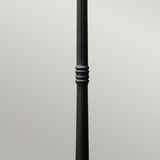 The Ledbury 1 Light Lamp Post in black features a single, tall metal pole with an elegant decorative design in the middle, evoking a heritage lantern style against a plain gray background.