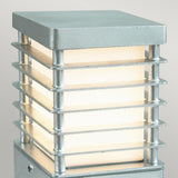 The Halmstad Small Bollard - Silver is a modern outdoor lamp made from galvanized steel, boasting a rectangular frame with horizontal slats. Its frosted glass interior not only provides illumination but also enhances its contemporary style, all while maintaining an IP65 rating for outstanding durability against the elements.