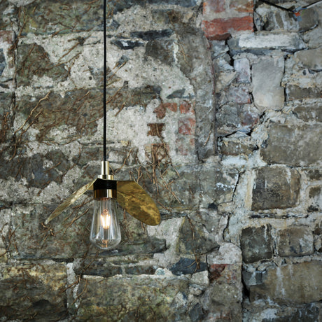 Hali Brass Pendant Light IP65 with wing-shaped blades and teardrop glass shade over an E27 bulb, hanging against a stone wall background.