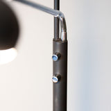 Close-up of the Vegas LED Combi Floor Lamp in black, showing the matte black column with two chrome control buttons and a flexible chrome reading arm.