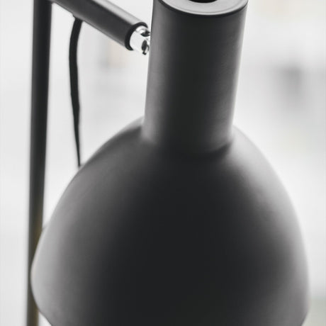 Close-up of the Baltimore Floor Lamp in black, showing the matt black cone shade's rounded shoulder, swivel knuckle, and slim rail against a plain light background.