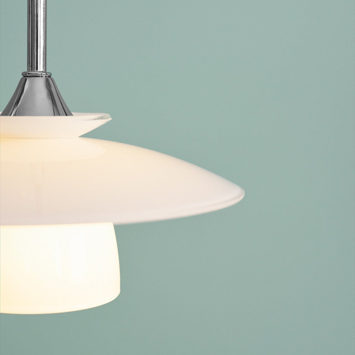 Scandinavia Pendant Light 20cm in opal and chrome, close-up of stacked opal glass plates lit from within beneath a polished chrome cone, set against a light teal background.