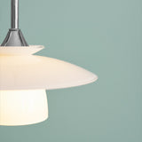 Scandinavia Pendant Light 20cm in opal and chrome, close-up of stacked opal glass plates lit from within beneath a polished chrome cone, set against a light teal background.
