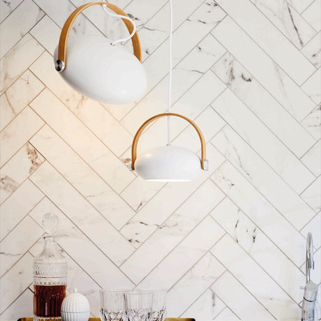 DC Pendant Light 26cm in white and oak, egg-shaped shade with curved wood handle strap, shown in pairs above a kitchen bar against herringbone marble tile.