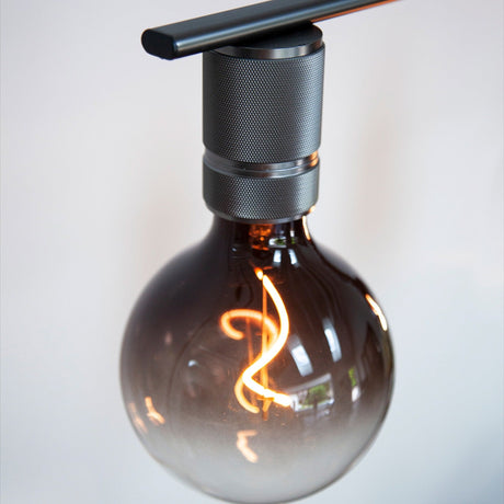 Halo 5 Light Chandelier in gunmetal, close-up of a knurled cylinder holder beneath a black bar, holding a smoked glass globe bulb with visible glowing filament.