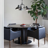 Metropole 3 Light Flush Ceiling Light in black, with dome-shaped shades on short arms and a central cone, hung above a round marble dining table in a living space.