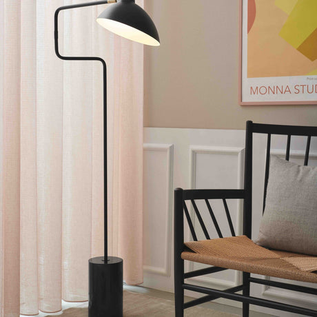 Metropole Deluxe Swing Floor Lamp in black with a wide dome shade, angled black rod, and cylindrical marble base, shown beside a bench and sheer curtains.