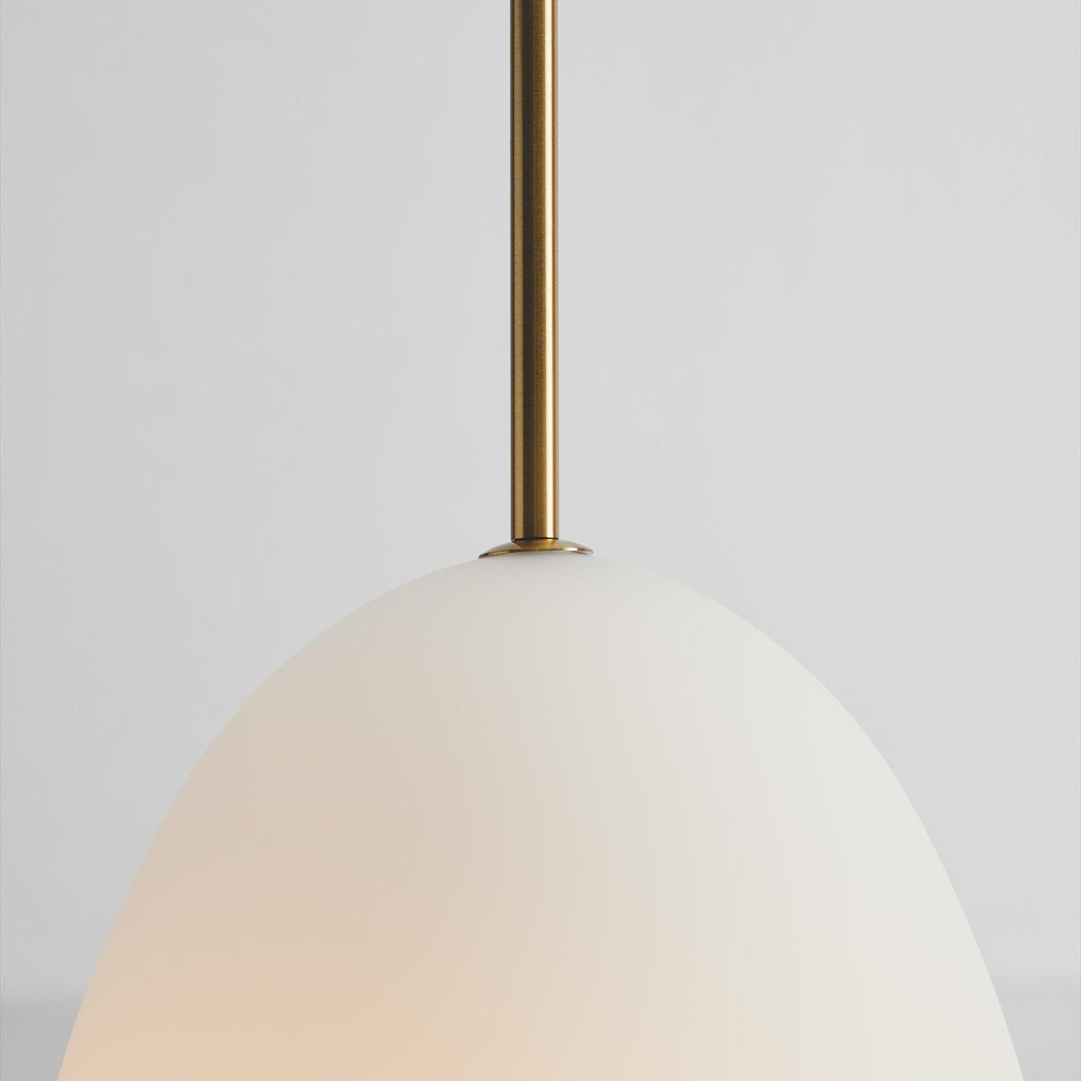 Bodø Pendant Light 20cm close-up showing the opal white egg-shaped glass shade and slim brass sleeve against a plain light grey background.