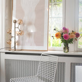Atom Glass 4 Light Table Lamp in antique brass with amber glass spheres branching from a slim stem, shown on a windowsill beside artwork and fresh flowers.