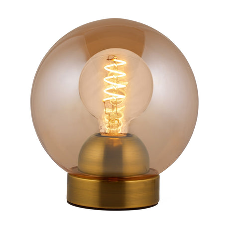 Bubbles Table Lamp 18cm in amber, a round amber glass globe on a low brass base with a lit spiral filament bulb visible inside, shown on a white background.