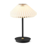 Paris LED Go Clean Rechargeable Table Lamp with white pleated paper shade, slim black stem, and round black base with brass accents on a plain white background.