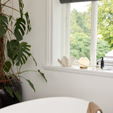 Stockholm LED Rechargeable Outdoor Table Lamp in marble grey with a brass base and ring handle, shown on a white windowsill beside a decorative shell ornament.
