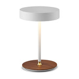 On the Move LED Rechargeable Table Lamp in white, featuring a round drum shade on a slim glowing stem with a brass collar and walnut disc base, on a plain white background.