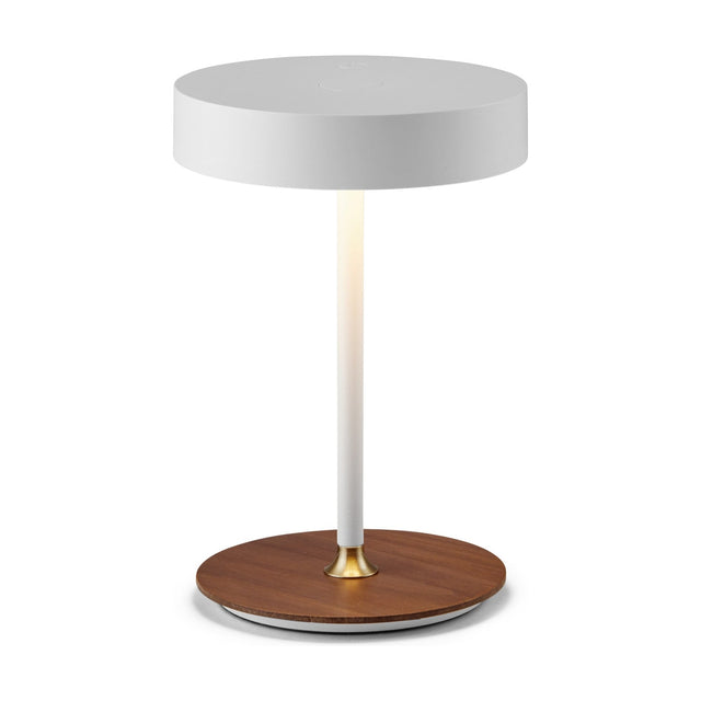 On the Move LED Rechargeable Table Lamp in white, featuring a round drum shade on a slim glowing stem with a brass collar and walnut disc base, on a plain white background.