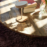 On the Move LED Rechargeable Table Lamp 13cm in white with round walnut base and brass collar, shown on a marble coffee table beside books and a glass vase.