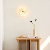 Stockholm LED Dimmable Flush Ceiling Light in grey marbled opal glass with a central brass boss, glowing softly on a wall above a wooden console table.