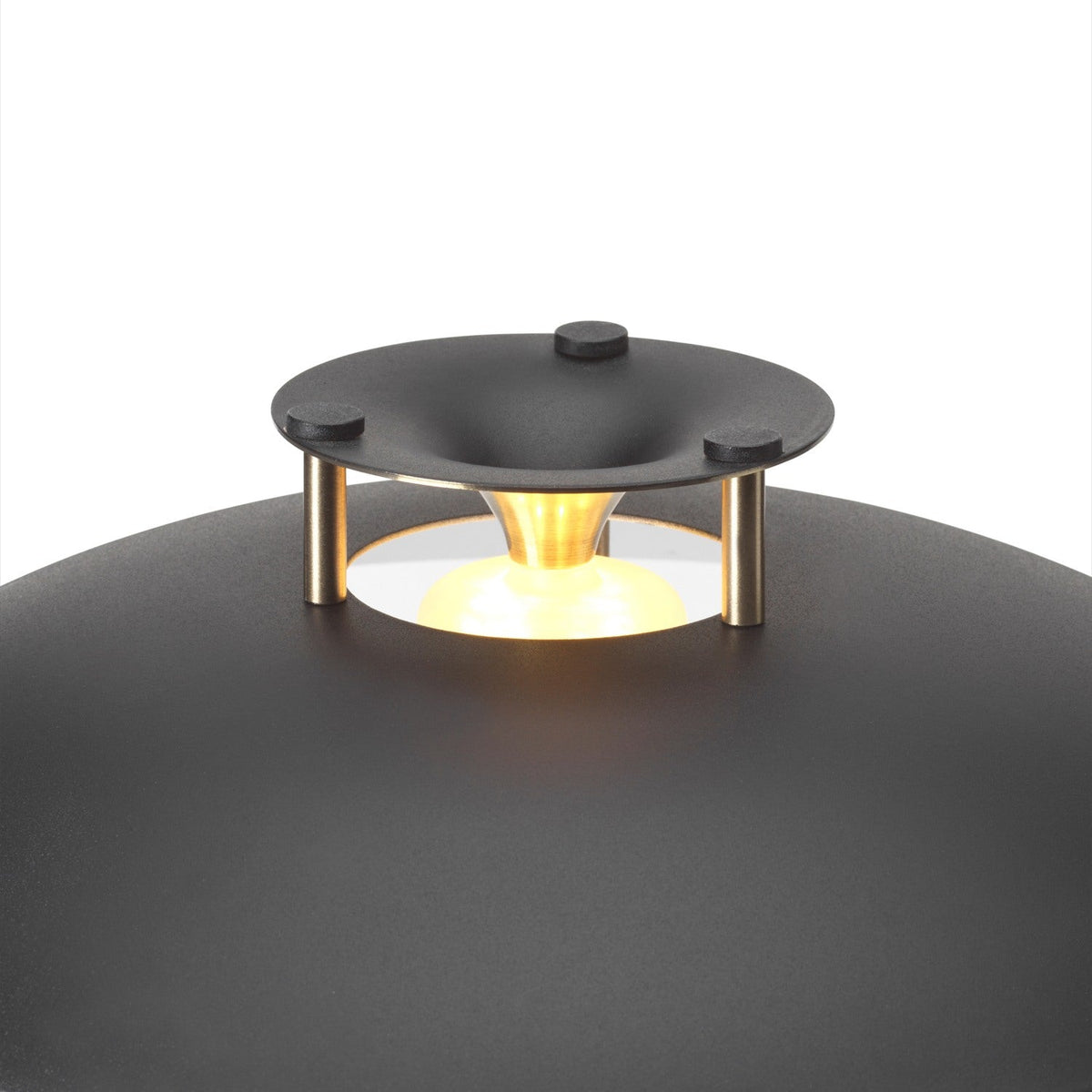 Close-up of the Stepp LED Outdoor Table Lamp in black, showing the shallow domed shade, black stepped cap on brass posts, and brass cone diffuser glowing above the curved base.