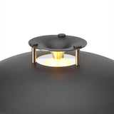 Close-up of the Stepp LED Outdoor Table Lamp in black, showing the shallow domed shade, black stepped cap on brass posts, and brass cone diffuser glowing above the curved base.