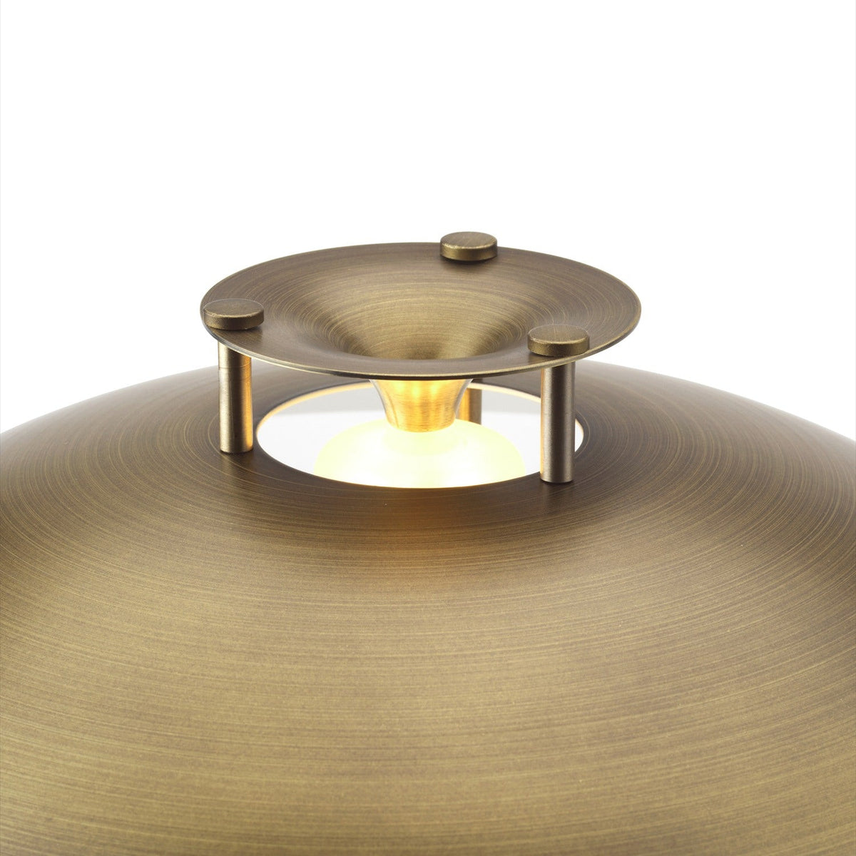 Close-up of the antique brass Stepp LED Outdoor Table Lamp, showing the domed shade with stepped brass cap on short posts and the glowing LED bulb beneath, on a plain white background.