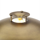 Close-up of the antique brass Stepp LED Outdoor Table Lamp, showing the domed shade with stepped brass cap on short posts and the glowing LED bulb beneath, on a plain white background.