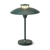 Stepp LED Outdoor Table Lamp in dark green, with a wide flared disc shade, brass accents, slim stem, and round base with power button, on a white background.