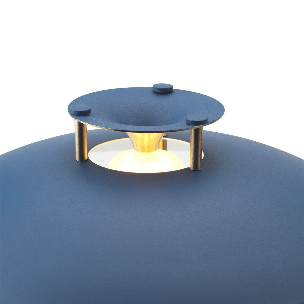 Close-up of the Stepp LED Outdoor Table Lamp in dark blue, showing the flat disc cap on brass posts glowing above the rounded blue base, set against a plain white background.