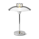 Stepp LED Outdoor Table Lamp in chrome, with a wide flat disc shade, stepped cap emitting a bright light ring, slim stem, and round base with brass collar on a white background.