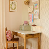 Mini Stepp LED Outdoor Table Lamp in terracotta with disc shade and slim stem, shown on a wooden desk in a child's bedroom styled with drawings and decor.