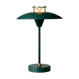 Mini Stepp LED Outdoor Table Lamp in dark green with a wide flat disc shade, stepped brass-accented cap, slim stem and round base, IP44 rated, shown on a plain white background.