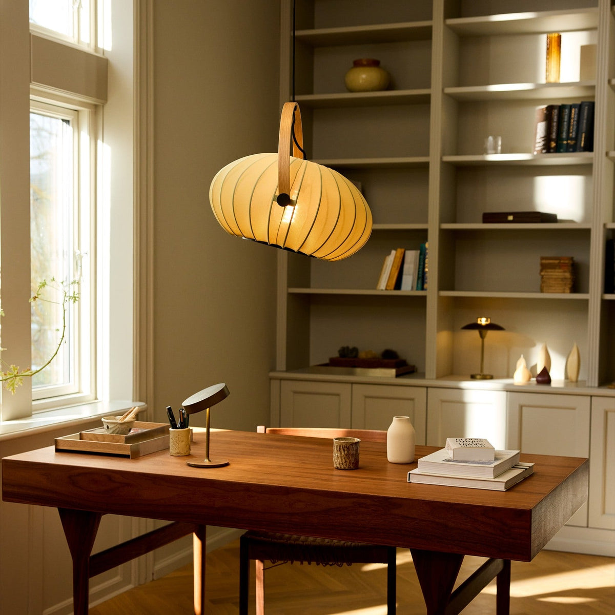DC Textile Forest Pendant Light 40cm in green fabric with ribbed shade and arched wooden handle, hanging over a wooden desk in a home office.