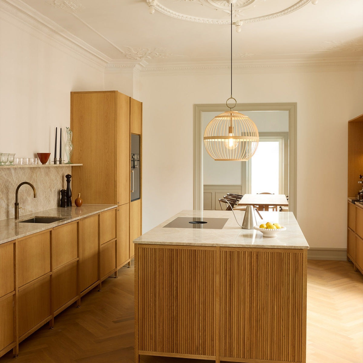 Stockholm Nordic Edition Pendant Light 50cm in natural woven bamboo with brass collar, hanging above a kitchen island in a wood and marble kitchen.