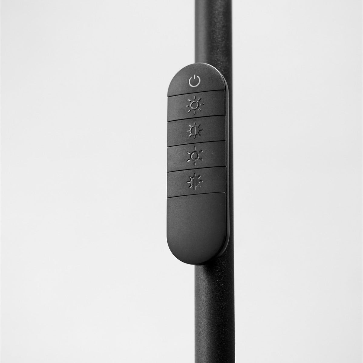 Close-up of the Slim LED Uplight Floor Lamp in black, showing the slim stem with an integrated control panel featuring power and four brightness buttons, on a plain background.