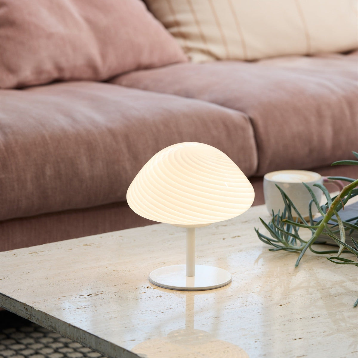 Mini Mush Glass Cable Table Lamp in white, with a ribbed opal glass dome shade on a slim stem and round disc base, shown lit on a marble coffee table beside a sofa.