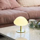 Mini Mush Glass Cable Table Lamp in olive green with a fluted glass dome shade, shown lit on a marble side table beside a sofa.