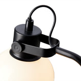 Close-up of the Glow Table Lamp's black metal fitting, showing the adjustable knuckle joint and band gripping the opal glass globe shade, on a white background.