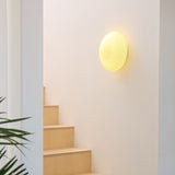 Candy Flush Ceiling Light 30cm in cream, a round wall-mounted opal glass dome with a spiral ribbed texture, glowing warmly beside a wooden staircase.
