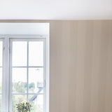 Bright window with white frame beside a wall in beige striped wallpaper, shown in a room corner with white ceiling.