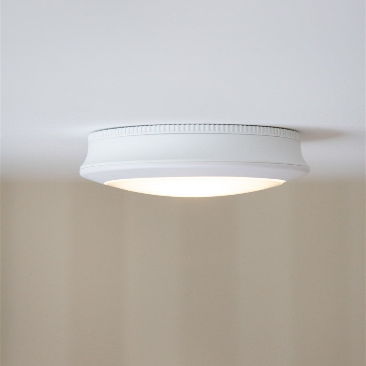 Push Rechargeable Flush Ceiling Light 18cm with Sensor in white, a round fitting with ribbed edge and prismatic diffuser, mounted flush on a plain white ceiling.