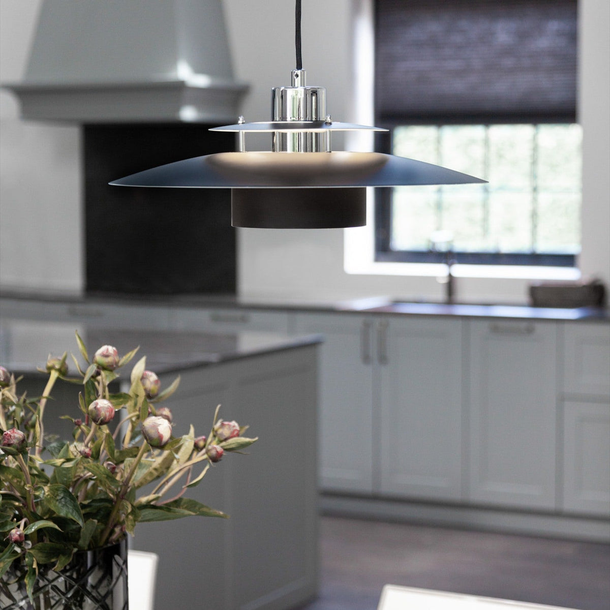 Sørup Pendant Light 40cm in black and chrome, tiered disc shade with chrome rings, hanging above a kitchen island in a light grey kitchen setting.