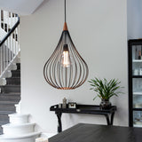 Drops Pendant Light 38cm in black and dark wood, a teardrop-shaped open wire cage with exposed bulb, hung above a dark table near a staircase and dining area.