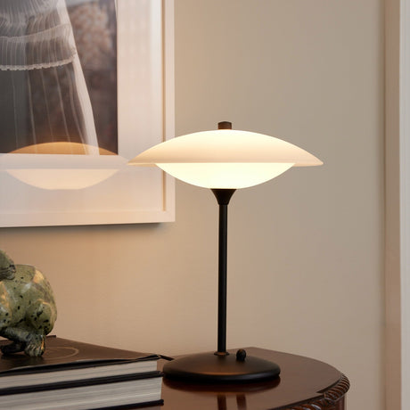 Baroni Glass Table Lamp 30cm in opal and black, lit on a wooden side table with a domed black base, slim stem, and rounded opal glass shade.