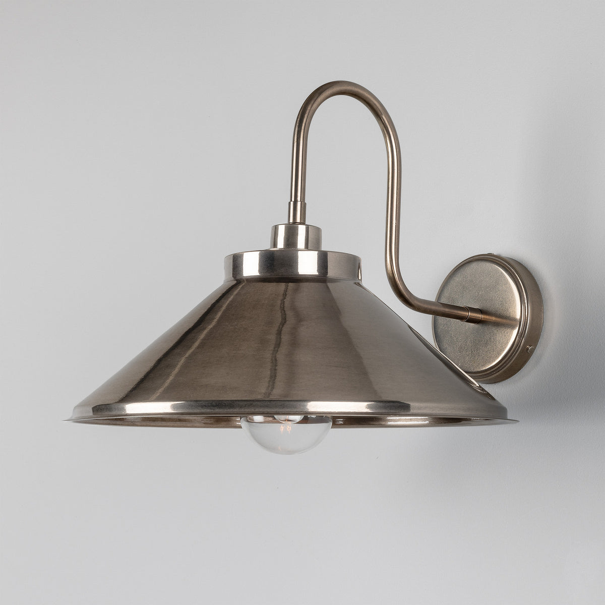 Halvery Brass Swan Neck Wall Light IP65, featuring a curved arm with round wall backplate and wide cone shade over a single exposed bulb, shown on a plain light grey background.