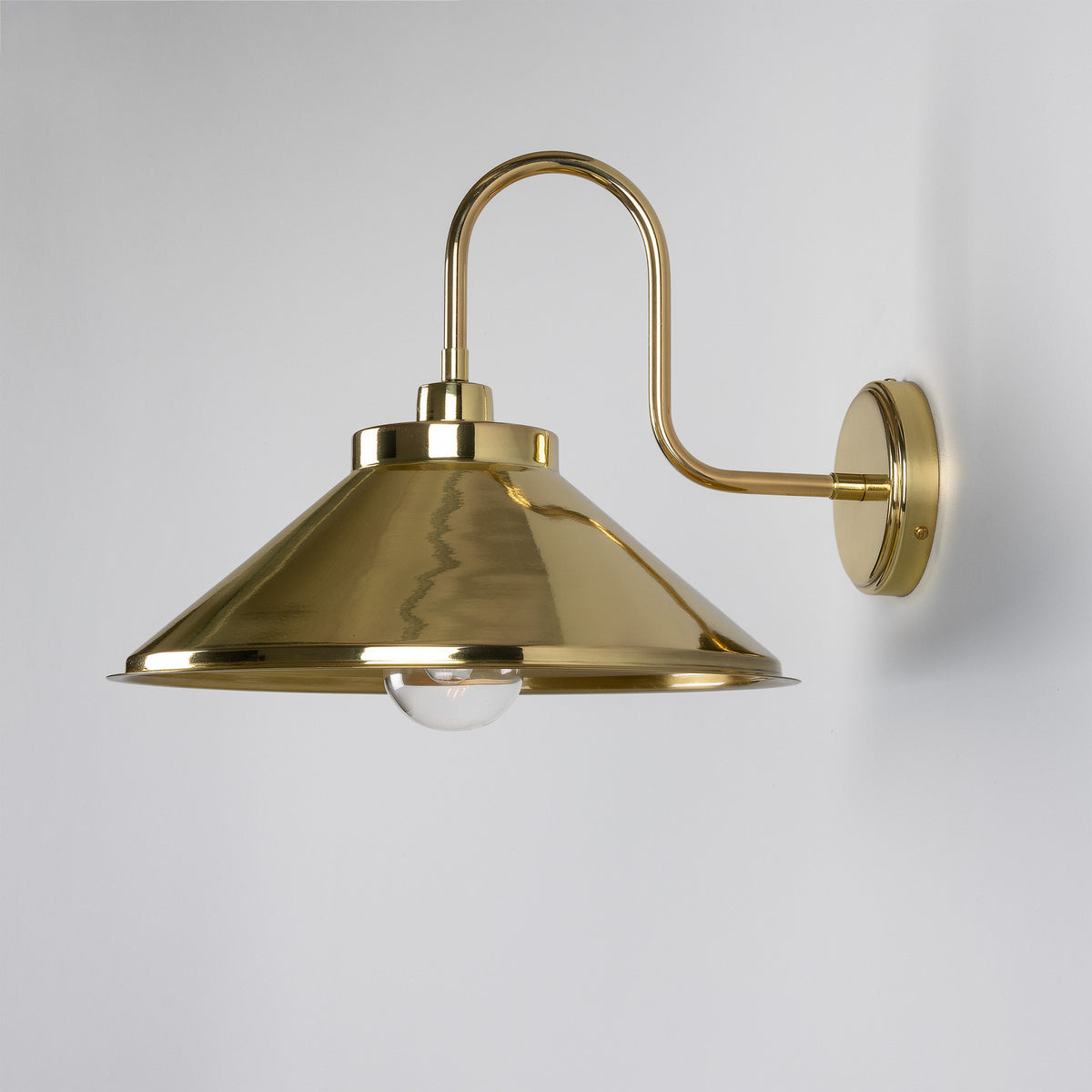Halvery Brass Swan Neck Wall Light IP65 with a round wall backplate, curved arm, and wide cone shade holding a single exposed bulb, shown on a plain white background.
