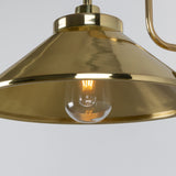 Close-up of the Halvery Brass Swan Neck Wall Light IP65, showing a wide cone metal shade in polished brass with a glowing E27 bulb visible beneath, set against a plain light background.