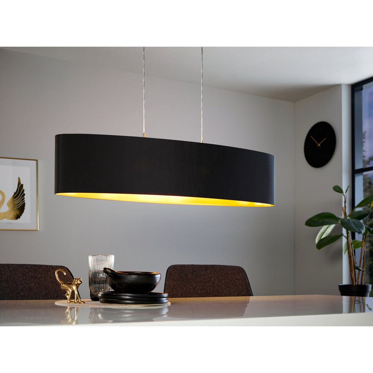 Hasanne Fabric 2 Light Pendant 100cm oval black fabric shade with gold lining, on satin nickel cables, shown above a dining table in a living room setting.