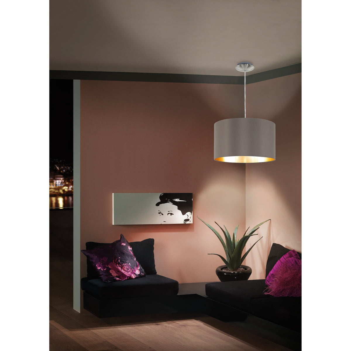 Hasanne fabric pendant light with mocha drum shade and gold inner lining, satin nickel ceiling canopy, shown suspended in a corner living room setting above a black sofa.